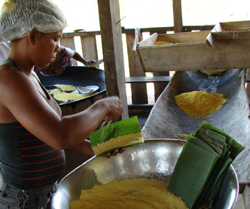 A co-op member coats palm leaves with a layer of cassava to make cassava chips. (photo by Stephanie Wolcott)