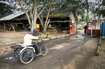Edson Lucas, who makes soaps and candles, hand-pedals himself several kilometers to and from his home in Kigambone.