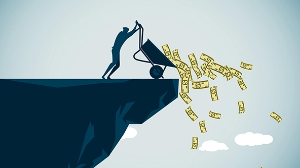 figure emptying a wheelbarrow of cash over a cliff