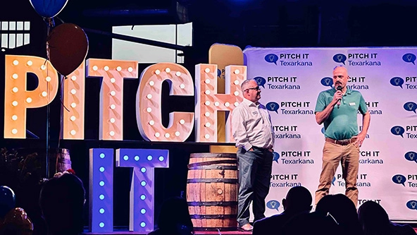 Two men on a stage next to the words 