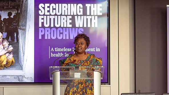 woman in traditional African dress speaking at a podium
