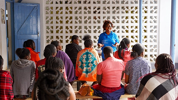 woman standing and speaking in front of a group of people