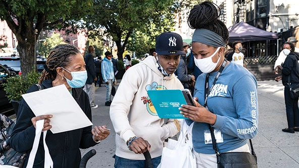 Three people standing outside filling out census forms on a tablet