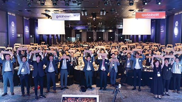 People wearing business attire and holding wooden nameplates in a conference room