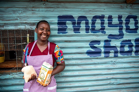 smiling woman holding products outside her retail shop