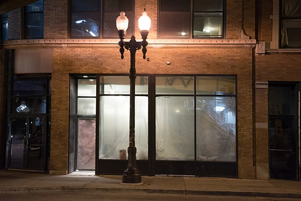 Empty abandoned urban city storefront and vintage street lamp at night.