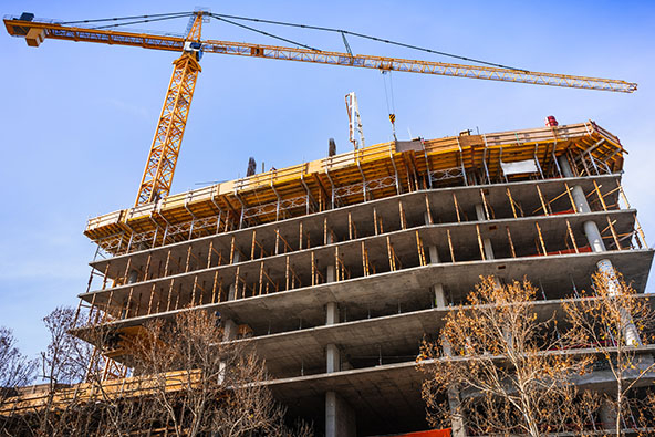 Multi-level concrete building under construction with tower crane