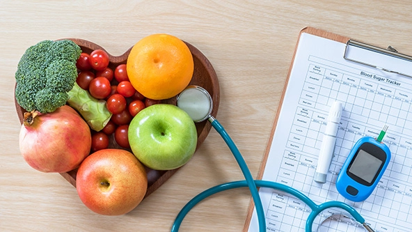 Fruits in a heart dish and patient's blood sugar control record with diabetic measuring tool kit