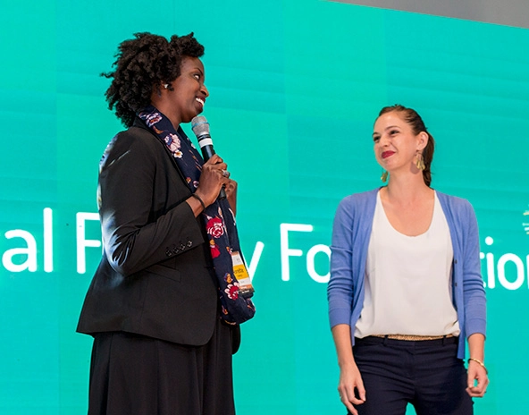 Black woman and white woman talking to one another on a stage