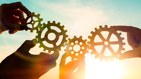 Four hands holding gears together to symbolize working collaboratively