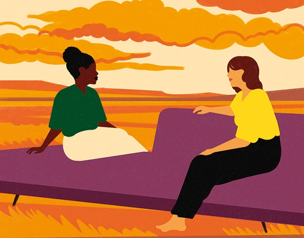 Two women talking while seated on a chaise lounge