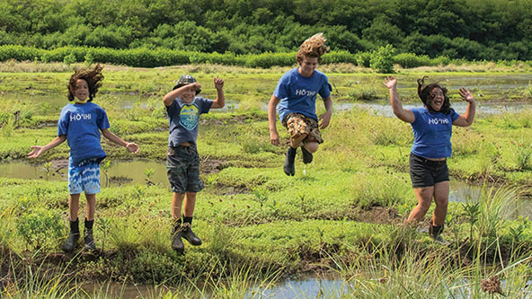 children jumping in the air at a fishpond