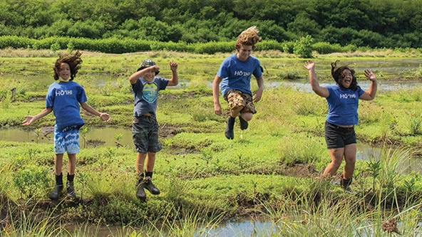 children jumping in the air at a fishpond