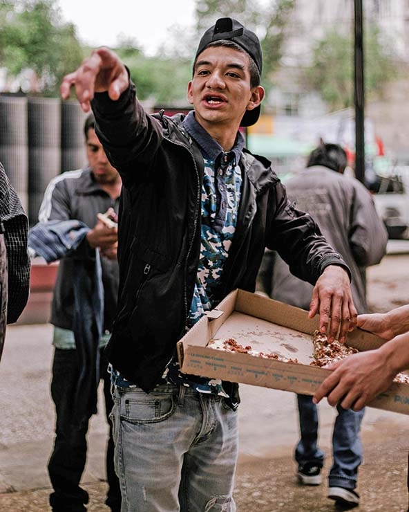 Man standing with open pizza box.