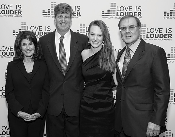Four people standing in front of a step-and-repeat banner with the words 