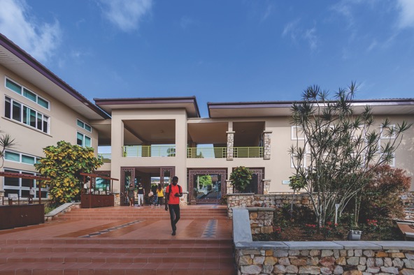 student in red shirt walking on campus at Ashesi University