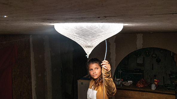 A girl's face is illuminated by a glowing glass bulb