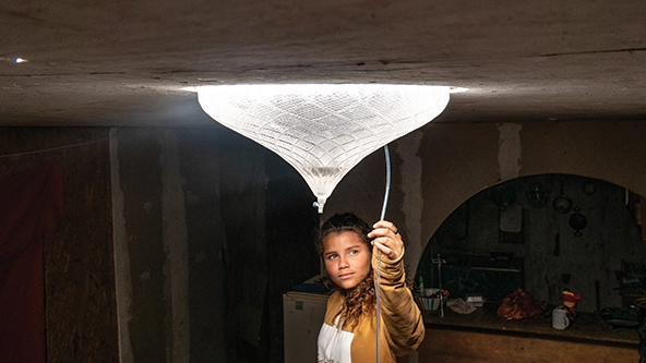A girl's face is illuminated by a glowing glass bulb